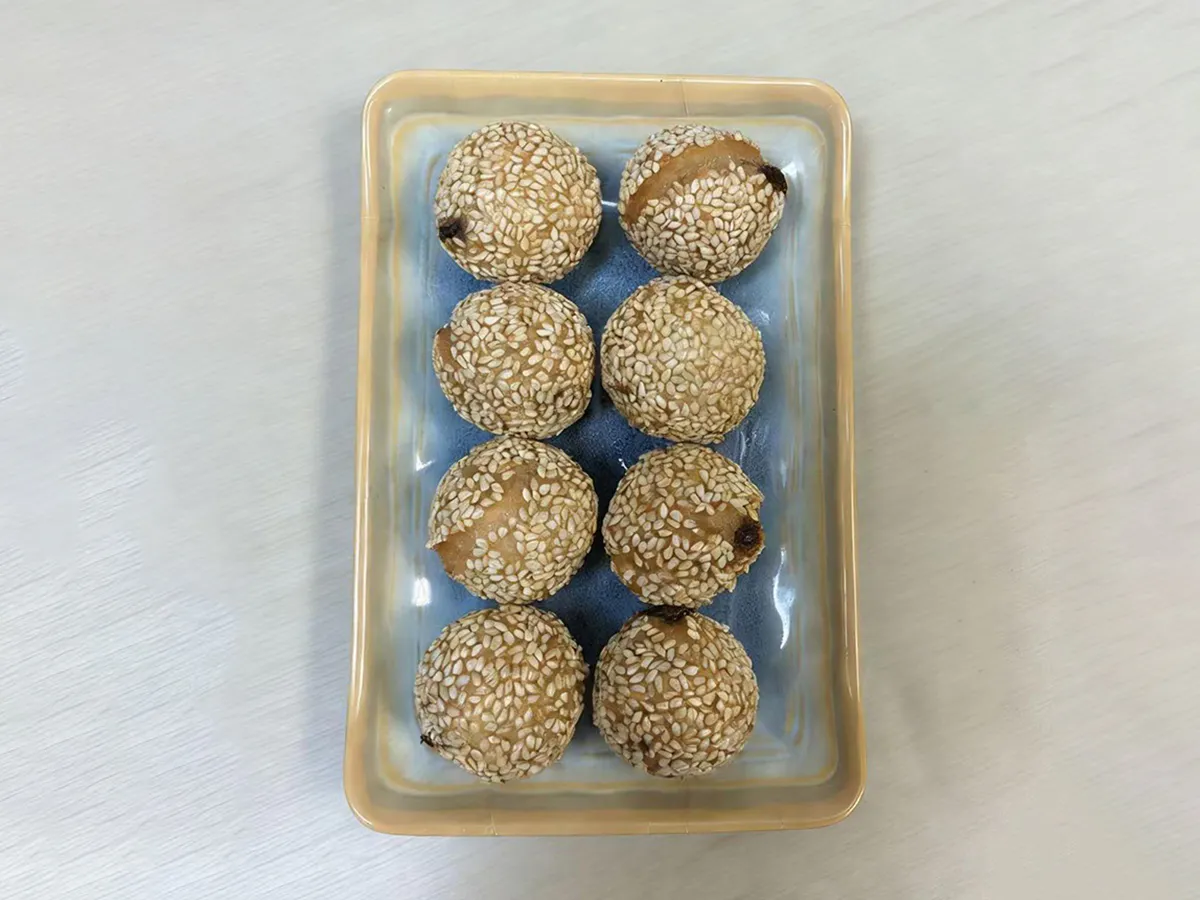 Eight glutinous sesame balls on a blue plate at Dumpling House, an Asian Restaurant in Harrisonburg