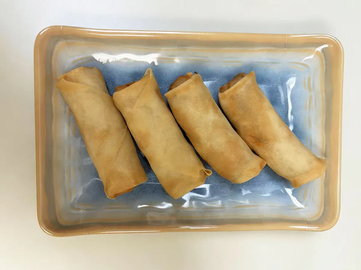 Four crispy spring rolls arranged neatly on a blue plate at Dumpling House, an Asian Restaurant in Harrisonburg