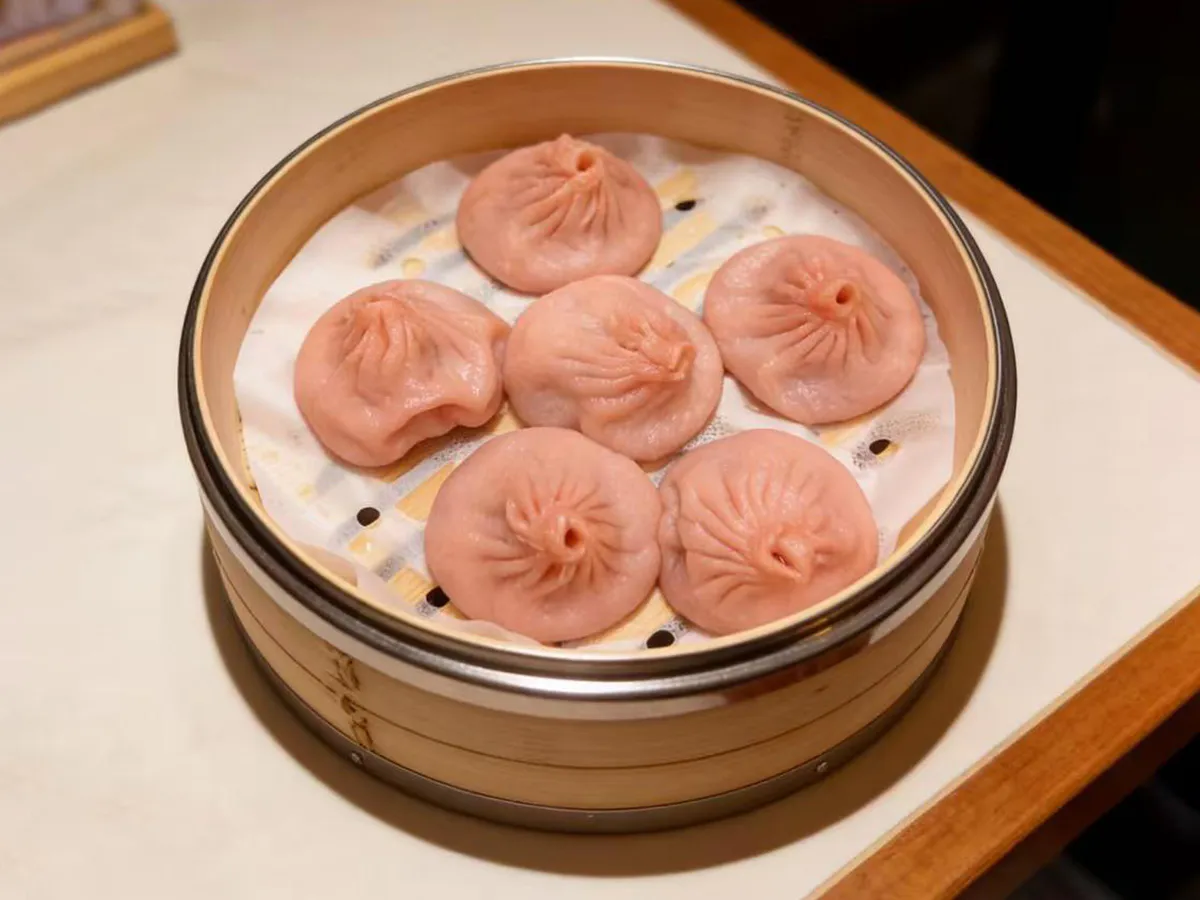 Six pink soup dumplings in a bamboo steamer at Dumpling House, an Asian Restaurant in Harrisonburg