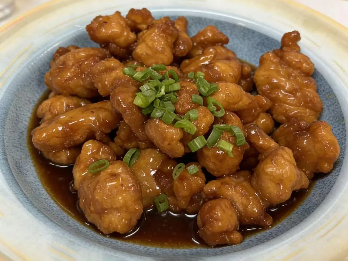Sweet and sour pork coated in glossy sauce, garnished with green onions at Dumpling House, an Asian Restaurant in Harrisonburg
